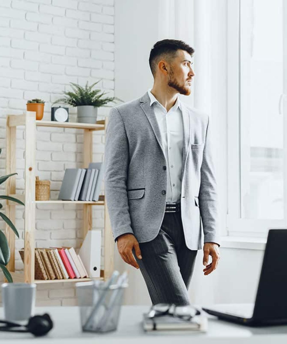 young-businessman-standing-by-the-window-at-his-of-2023-11-27-05-35-20-utc-copy.jpg